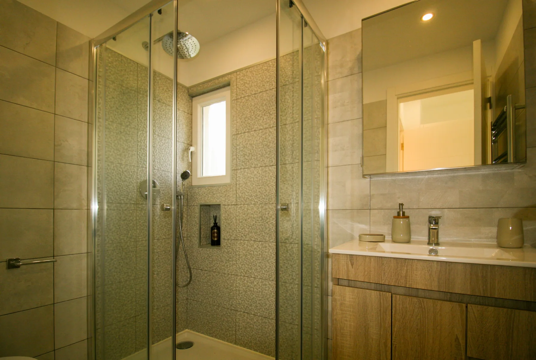 Un baño alicatado con ducha de vidrio y lavabo.