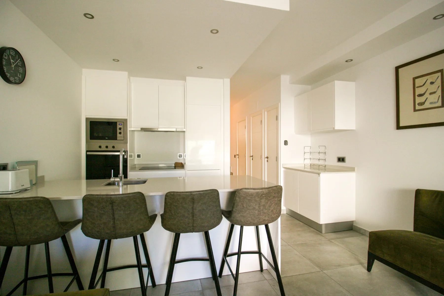 Una cocina y comedor luminosos con armarios blancos y asientos de barra.