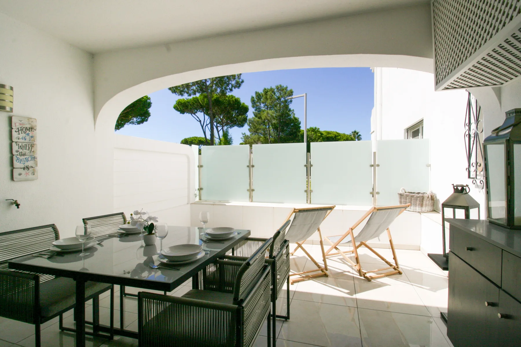 Una terraza soleada con asientos al aire libre y una mesa bajo un arco.