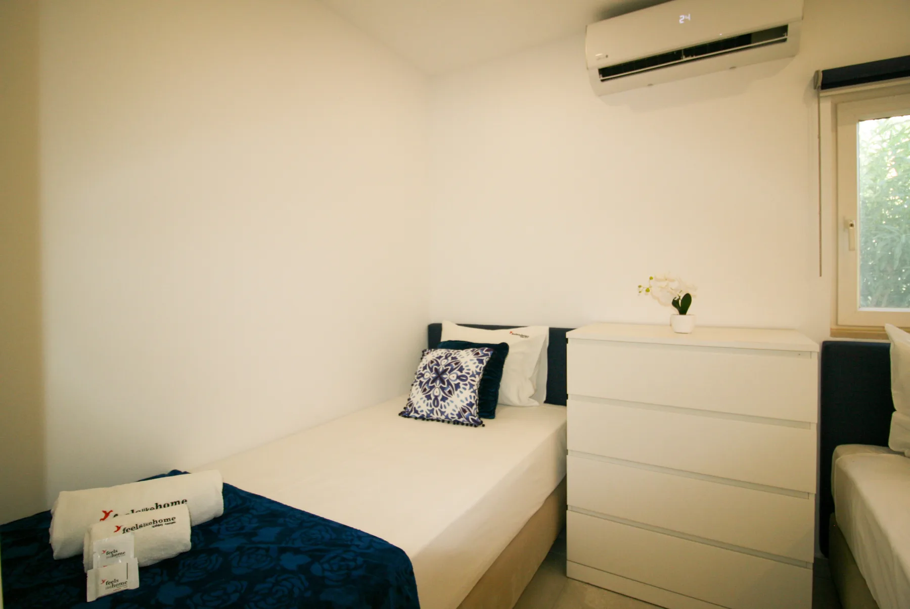 Un dormitorio con una cama, una cómoda y una ventana.