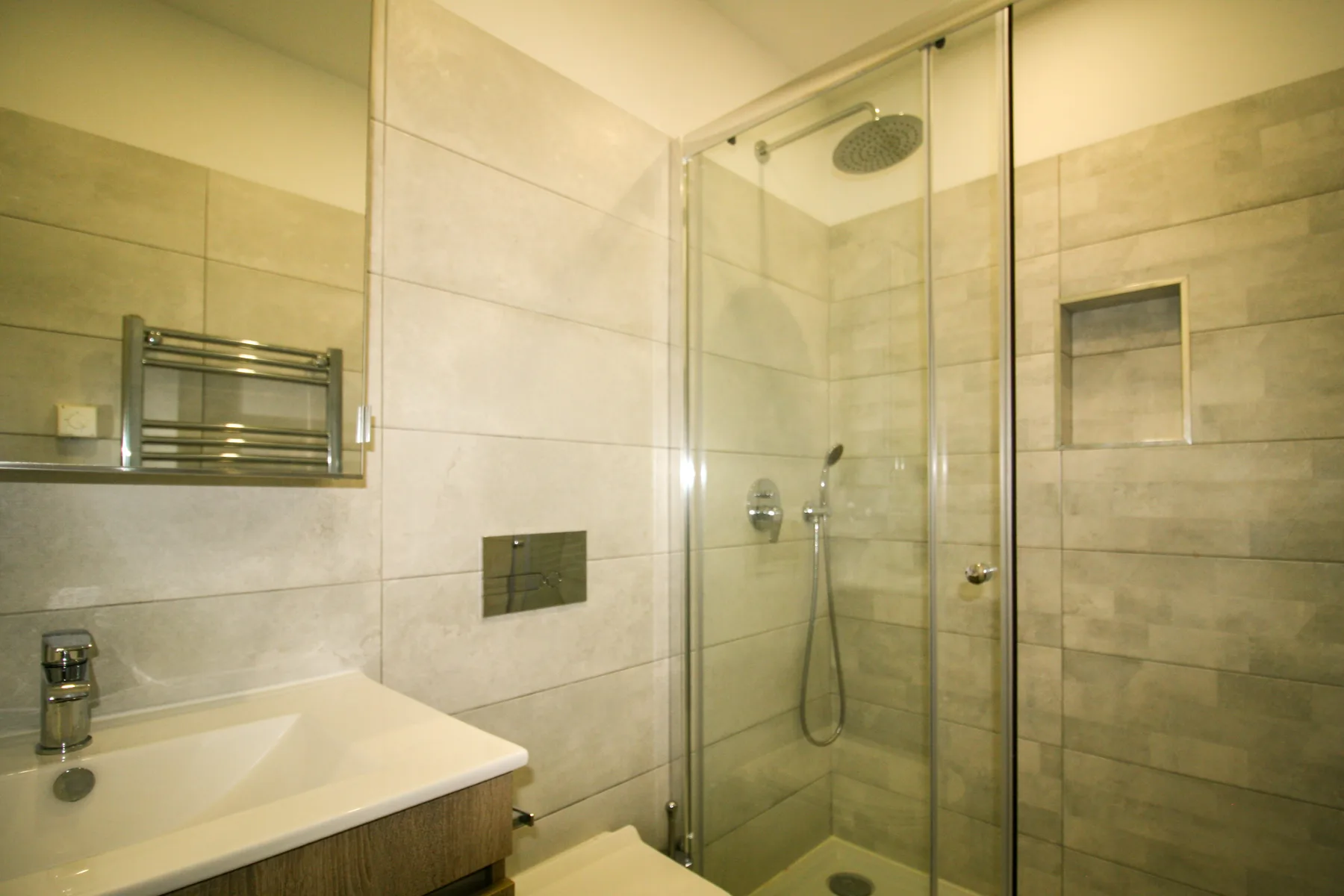 Un baño alicatado con lavabo y ducha con mampara de vidrio.