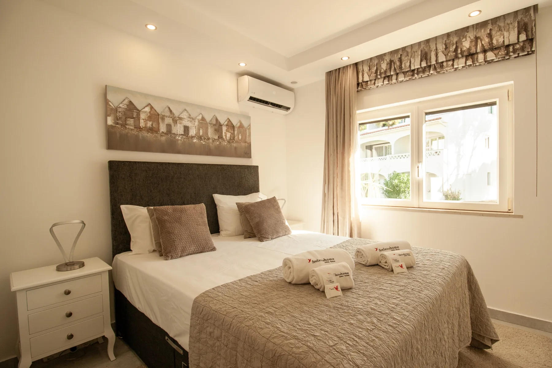 Dormitorio con una cama grande y una ventana con cortinas.