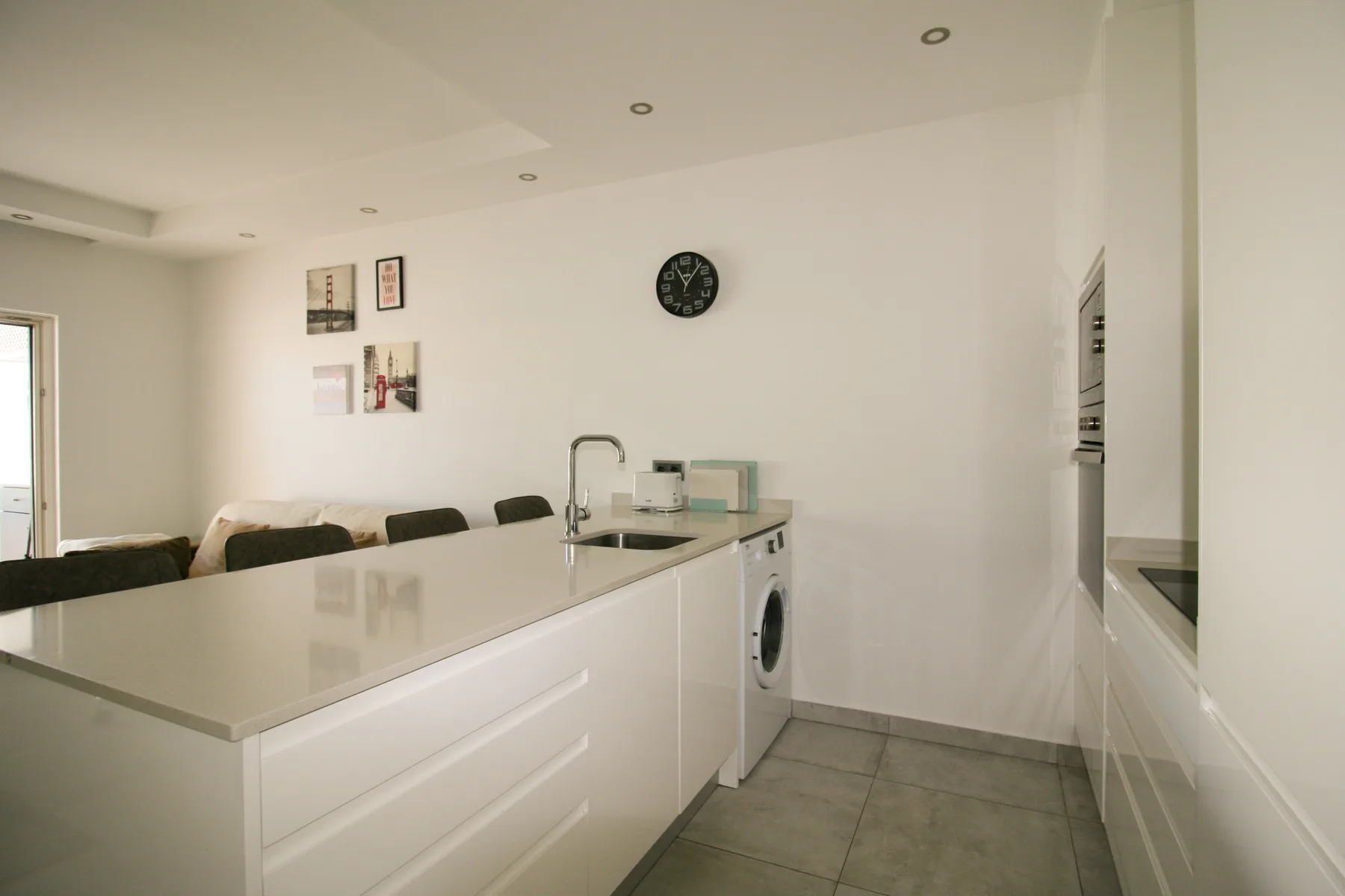 Una cocina luminosa con una encimera larga y un fregadero.