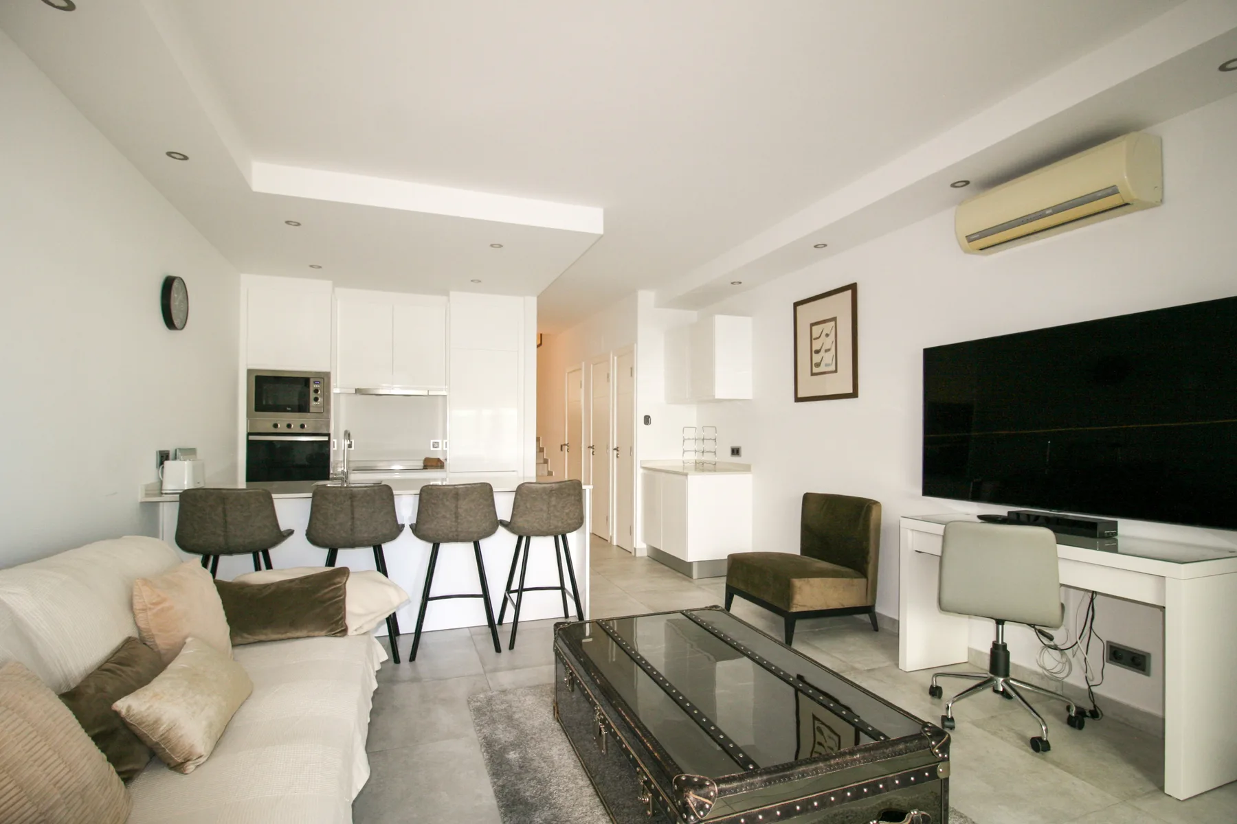 Sala de estar y cocina de concepto abierto, con asientos y un televisor.