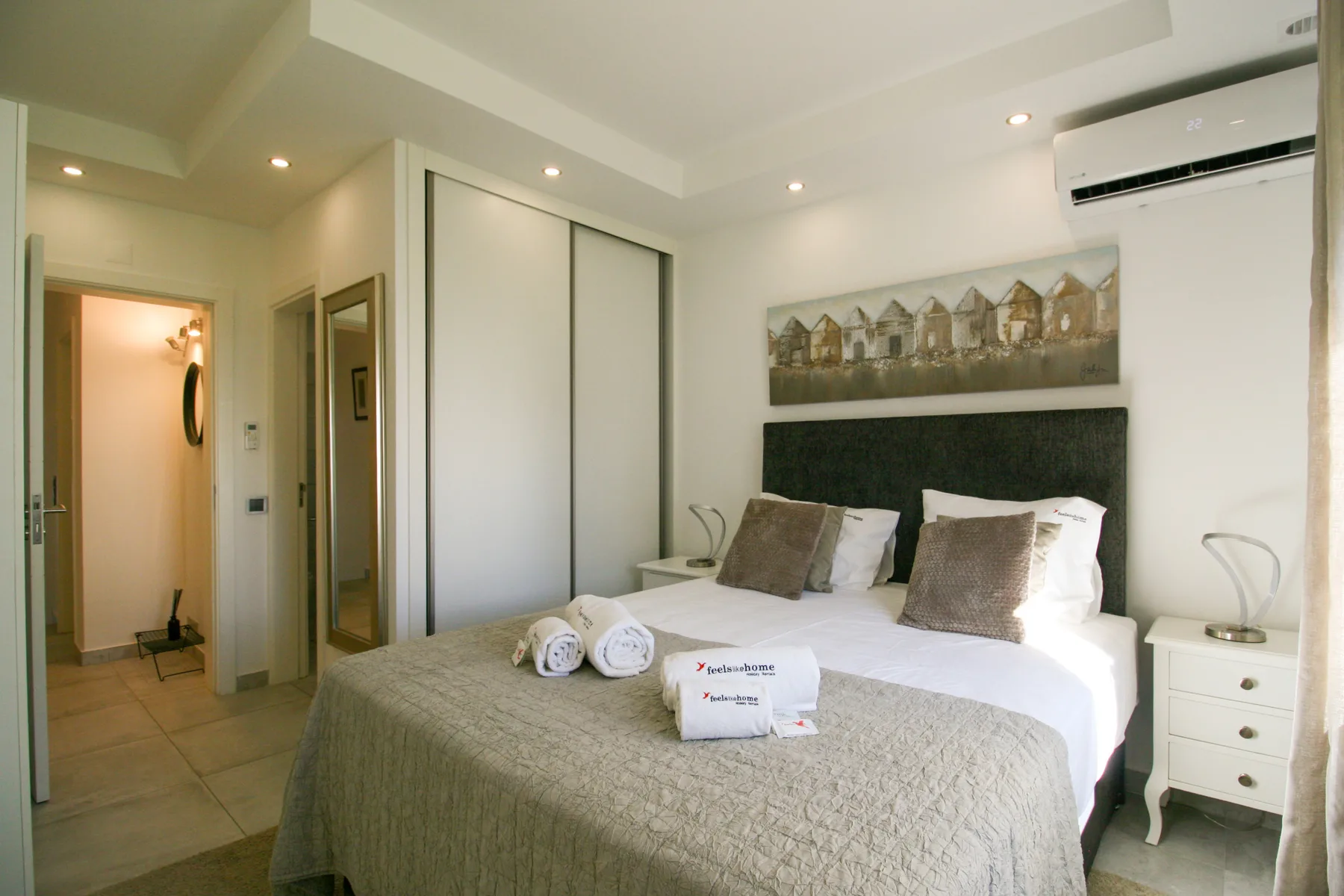 Dormitorio con una cama bien hecha y un cuadro sobre el cabecero.