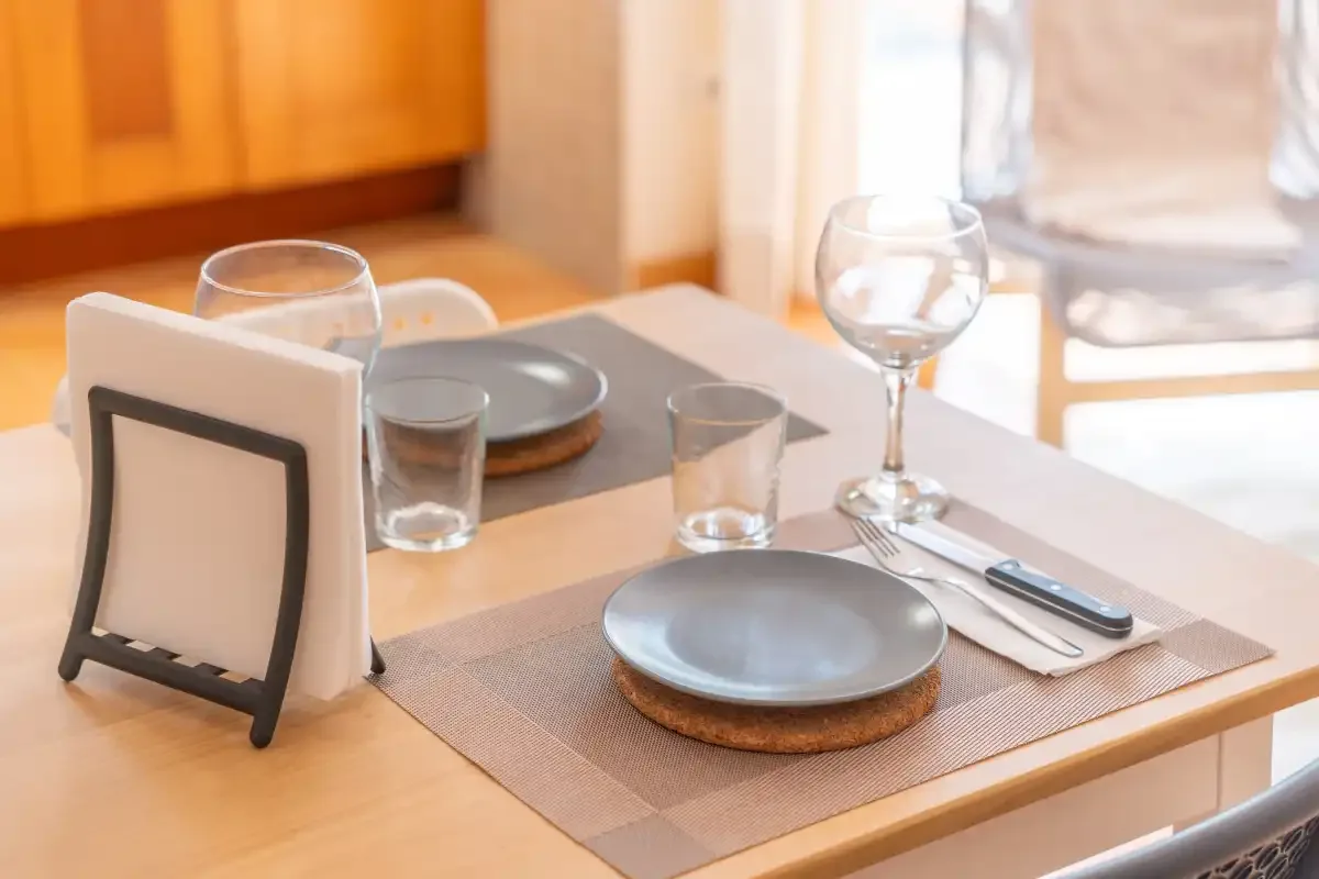 A dining table is set with plates, glasses, and cutlery.