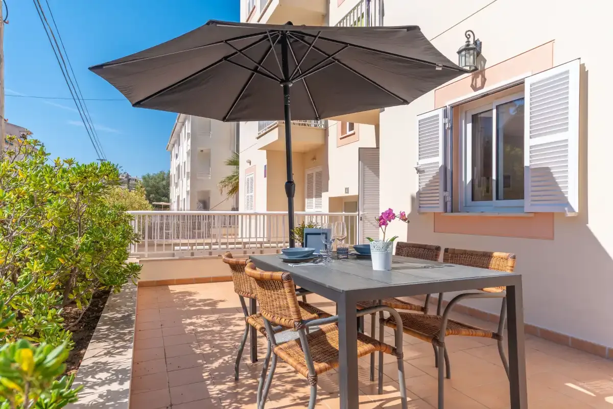 A patio dining area with a large dark umbrella beside a building.