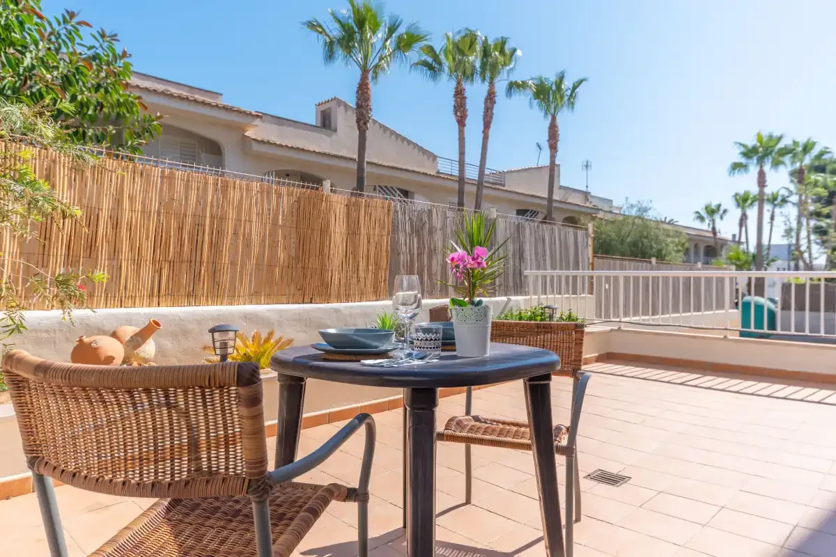 An outdoor dining area with a table and seating on a sunny patio.
