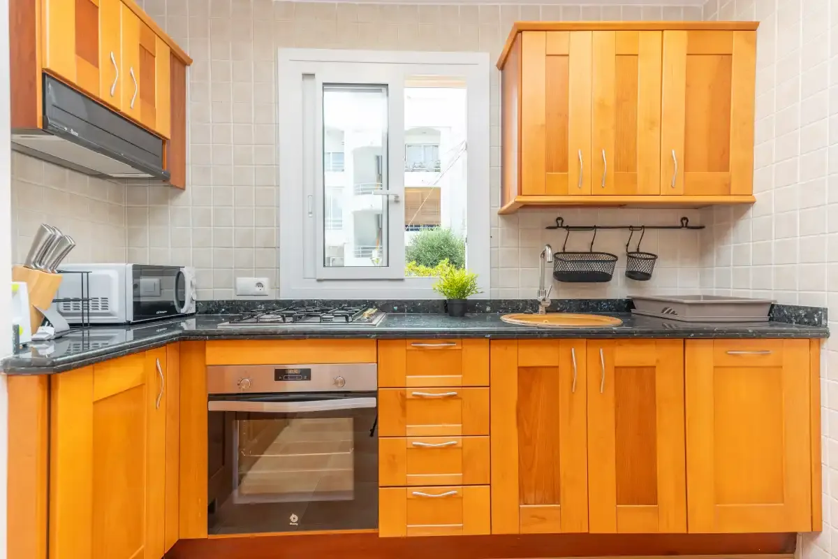 A kitchen with orange cabinets, a countertop, and a window.