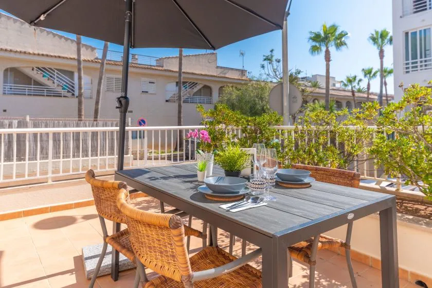 An outdoor dining area with a set table beneath a large umbrella.
