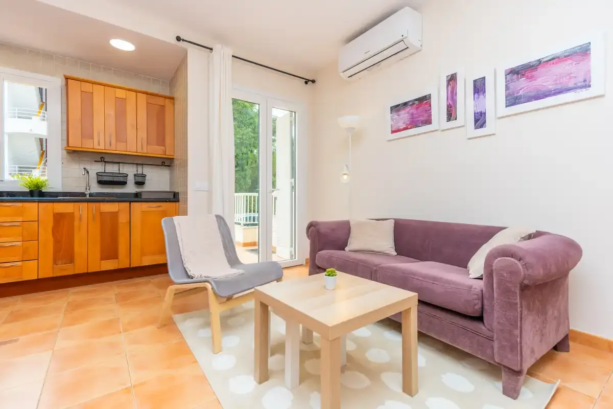 A living room with purple seating and a small coffee table beside the kitchen.