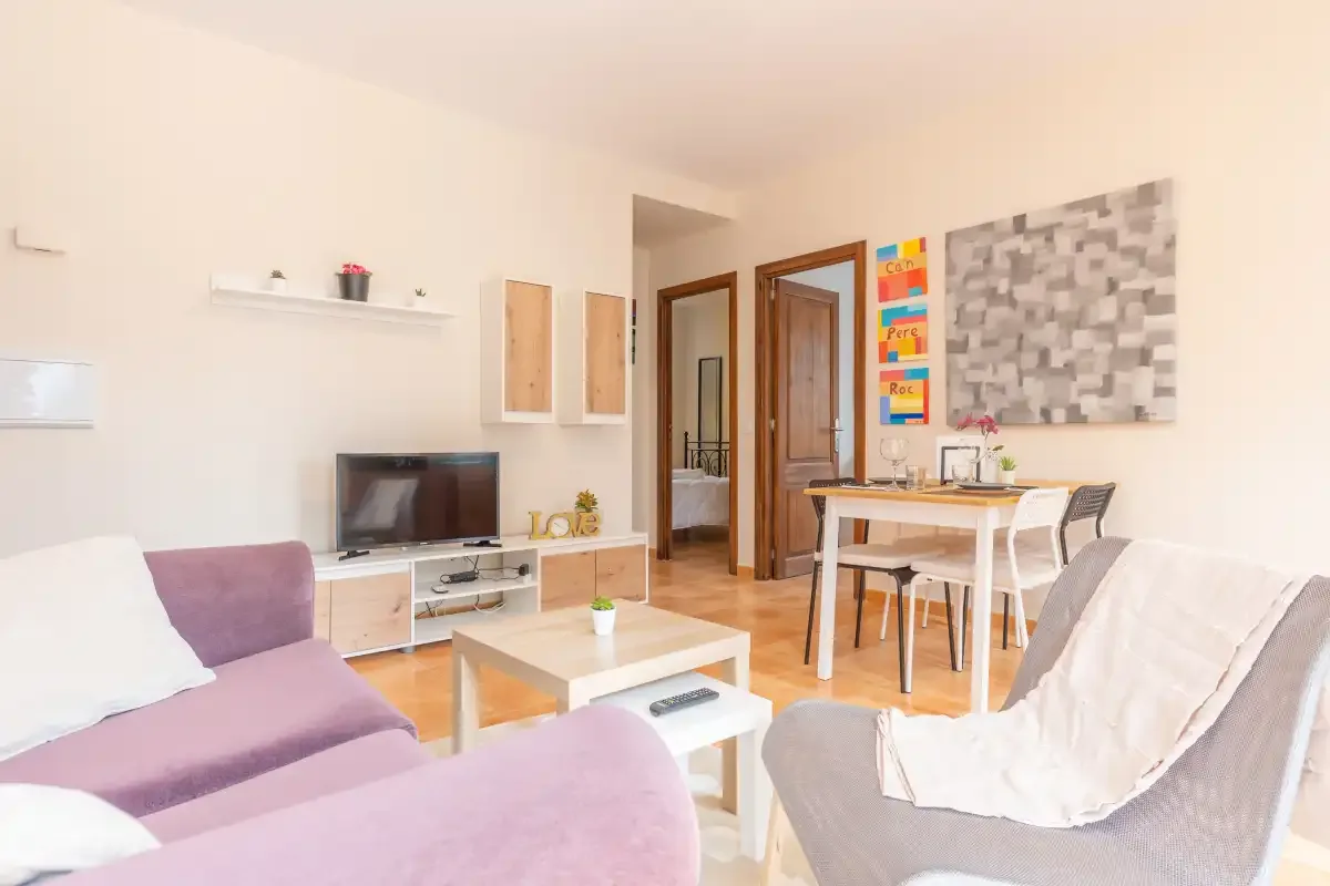 A living and dining area with seating, a television, and a table.