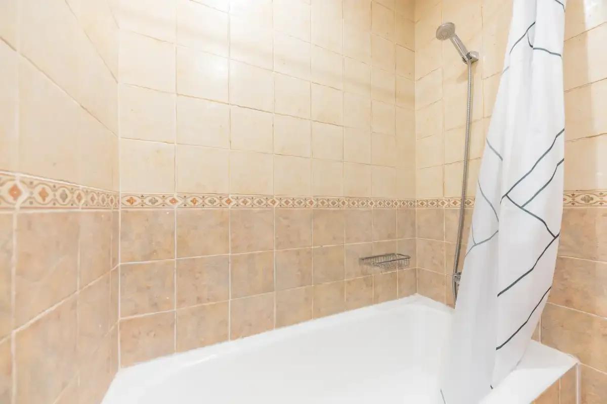 A tiled bathroom with a bathtub and shower curtain.