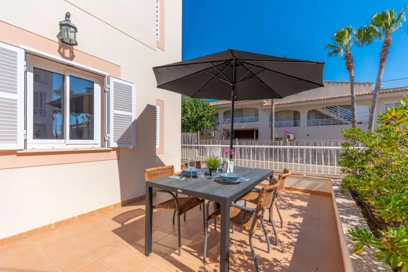 An outdoor patio dining area with a table beneath a large umbrella.