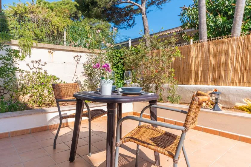 A tiled outdoor patio has a table and chairs beside planted borders.