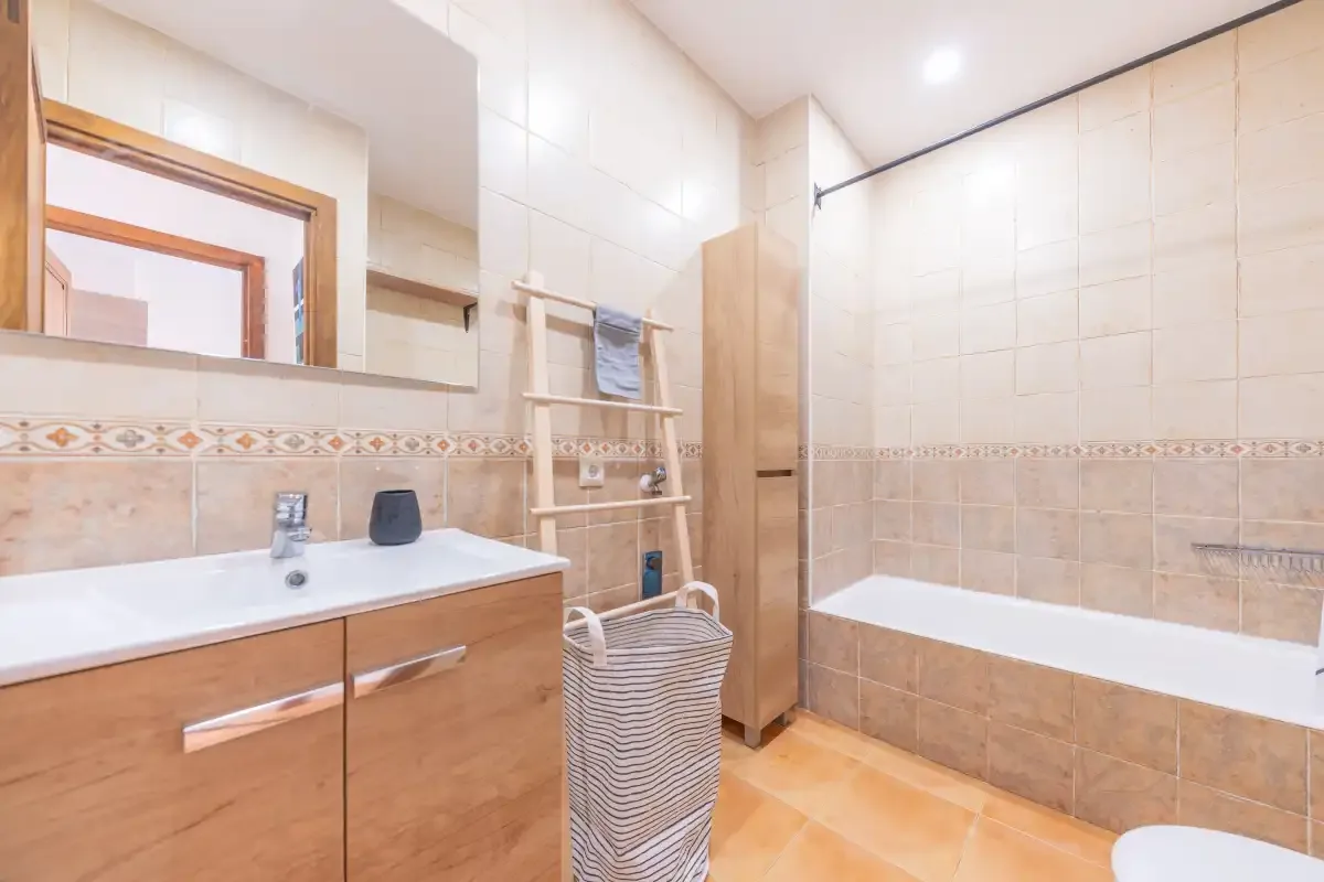 A bathroom with a sink, mirror, and bathtub.