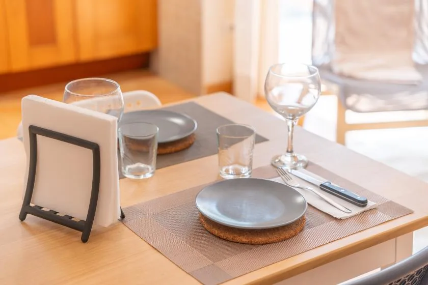 A dining table is set with plates, glasses, and cutlery.