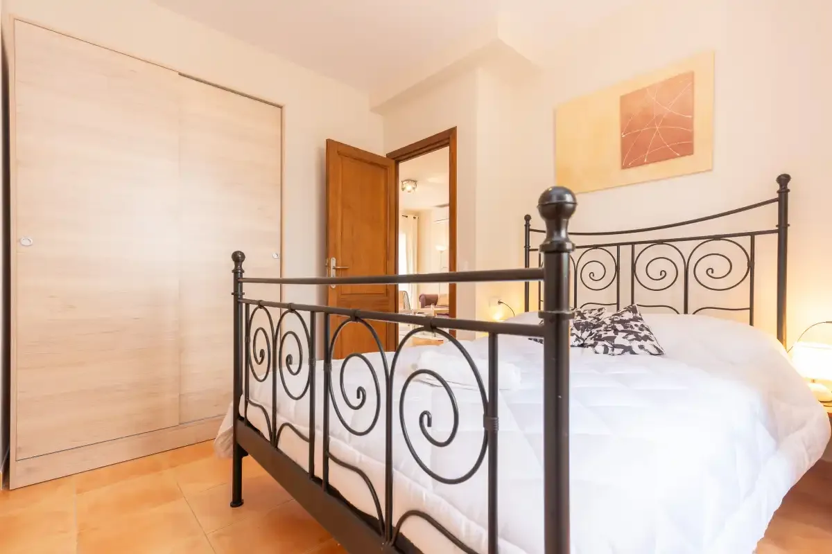 A bedroom with a bed featuring a black metal frame and white bedding.