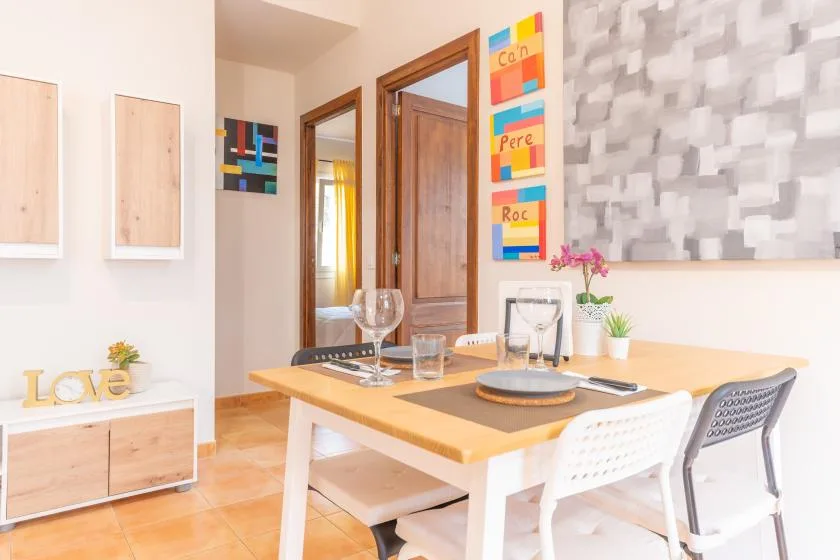 A dining area with a wooden table, chairs, and colorful wall art.