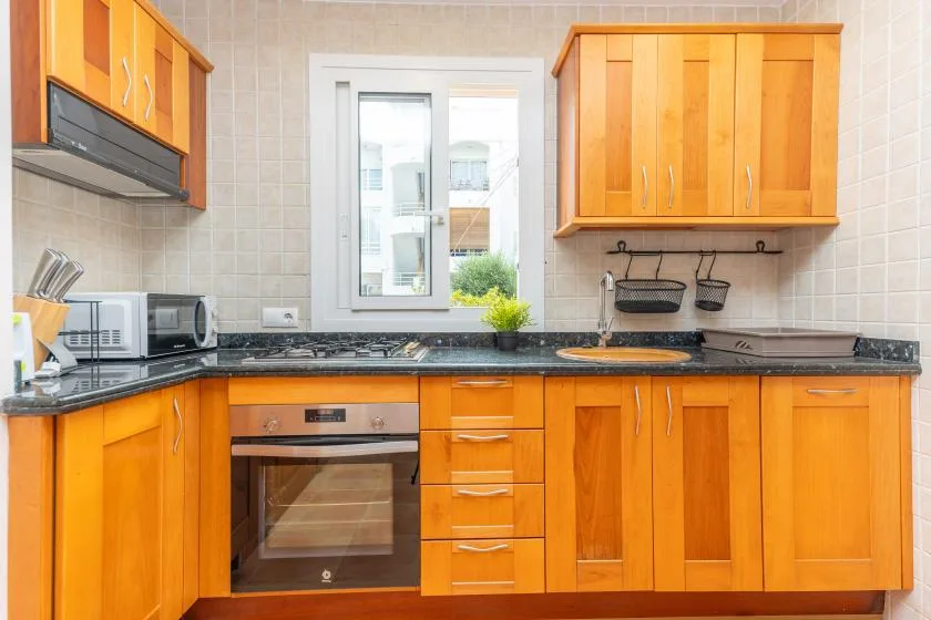 A kitchen with orange cabinets, dark countertops, and a window above the sink.