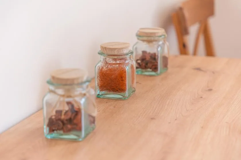 Small glass jars with spices sit on a wooden table.