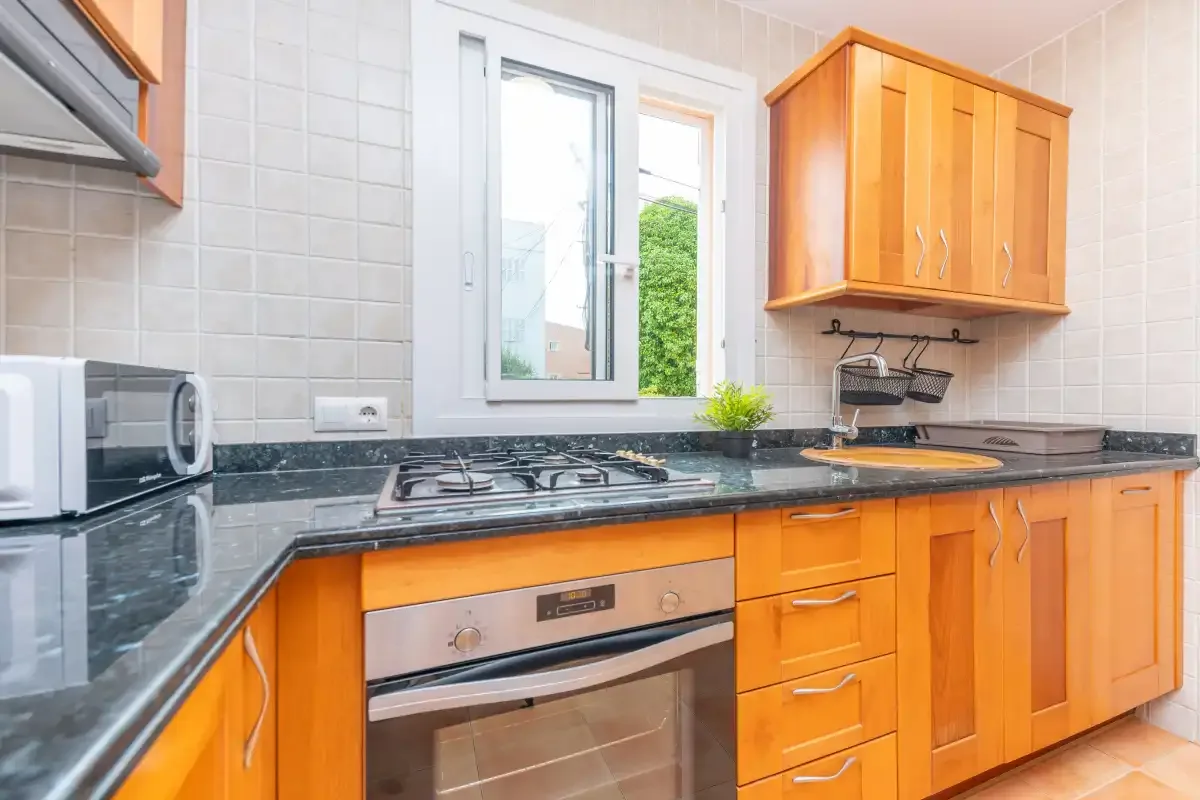 A bright kitchen with wooden cabinets and a countertop stove.
