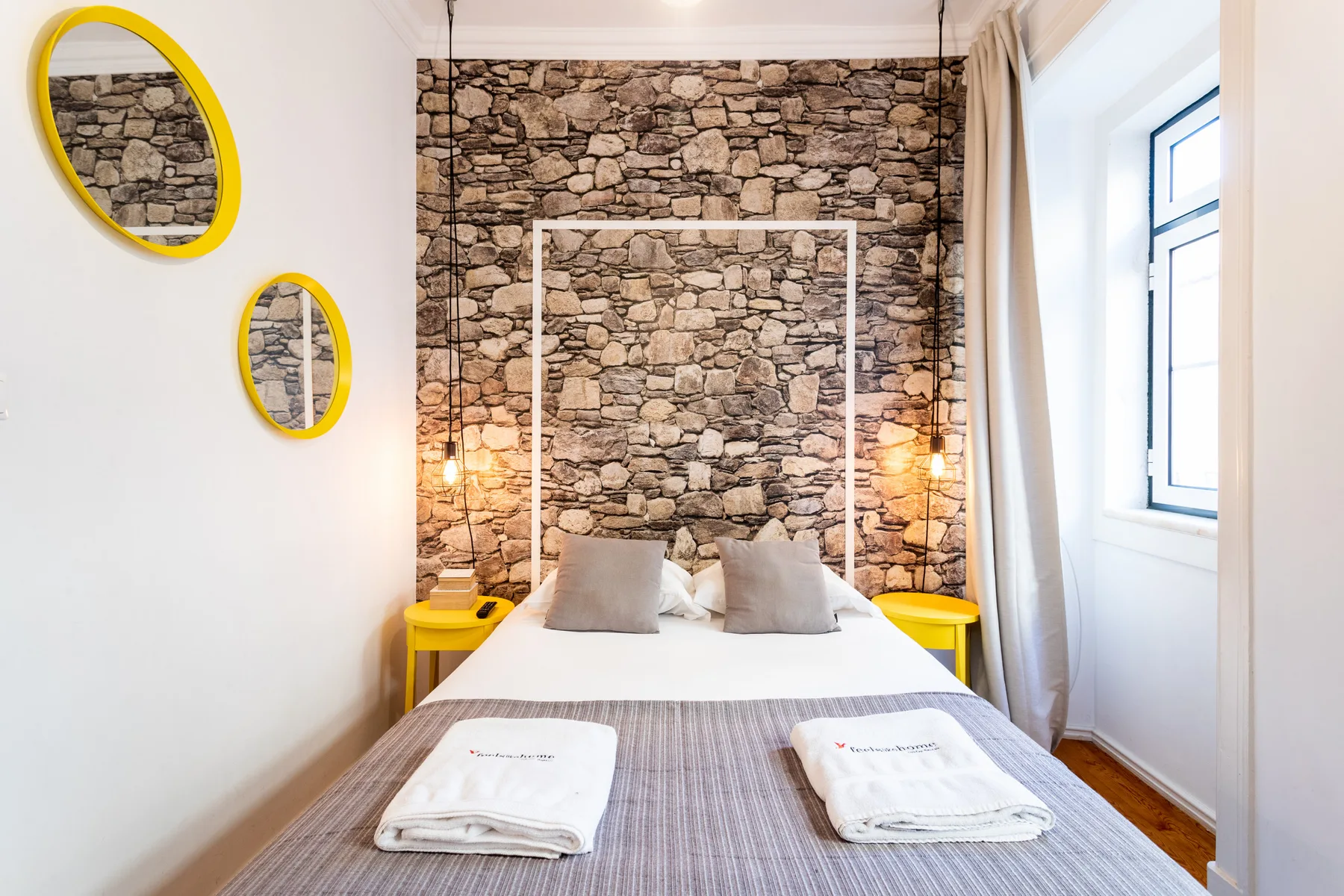 Un dormitorio con una cama frente a una pared con aspecto de piedra.