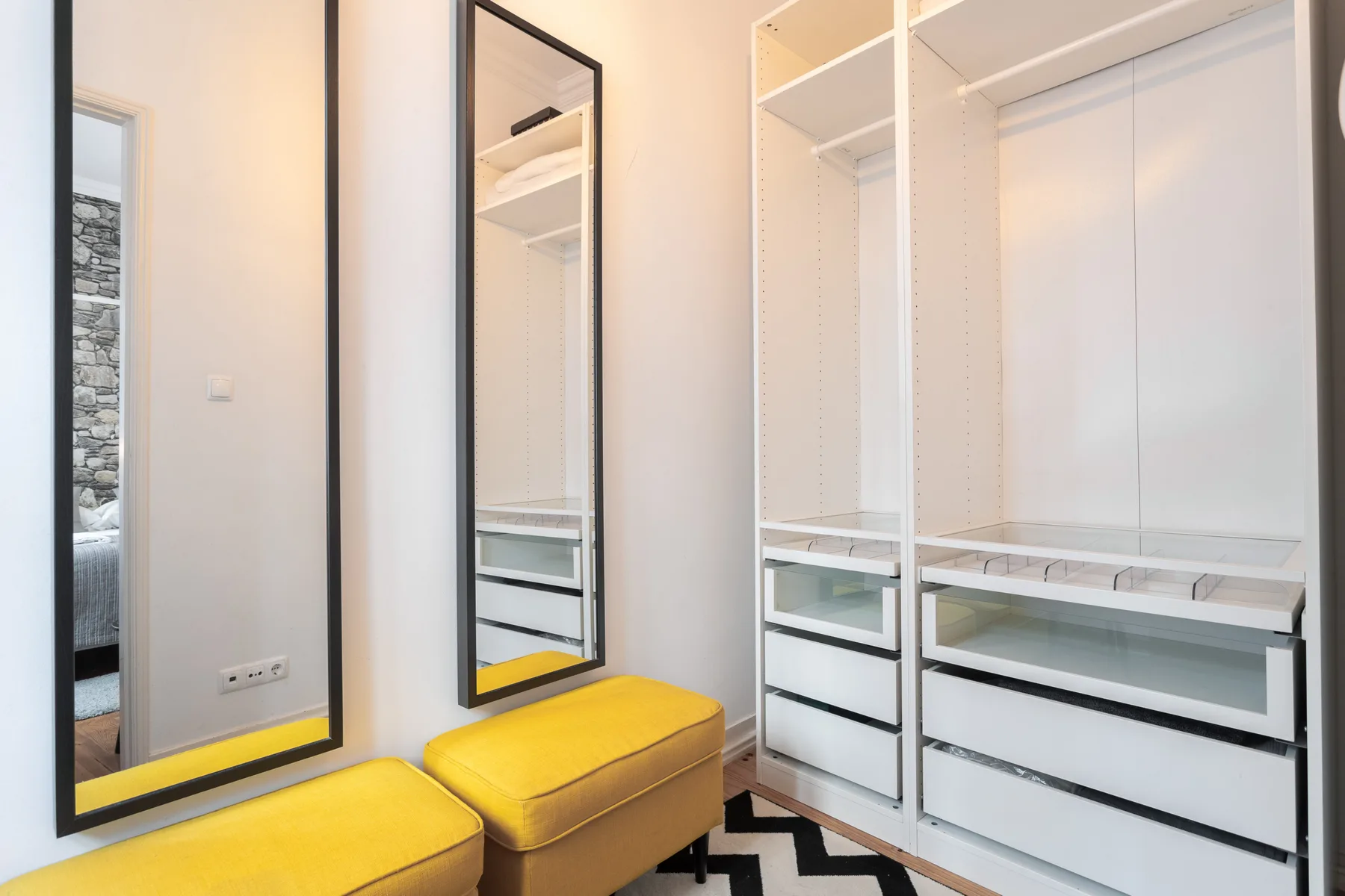 Una zona de vestidor con armarios empotrados y asientos color mostaza.