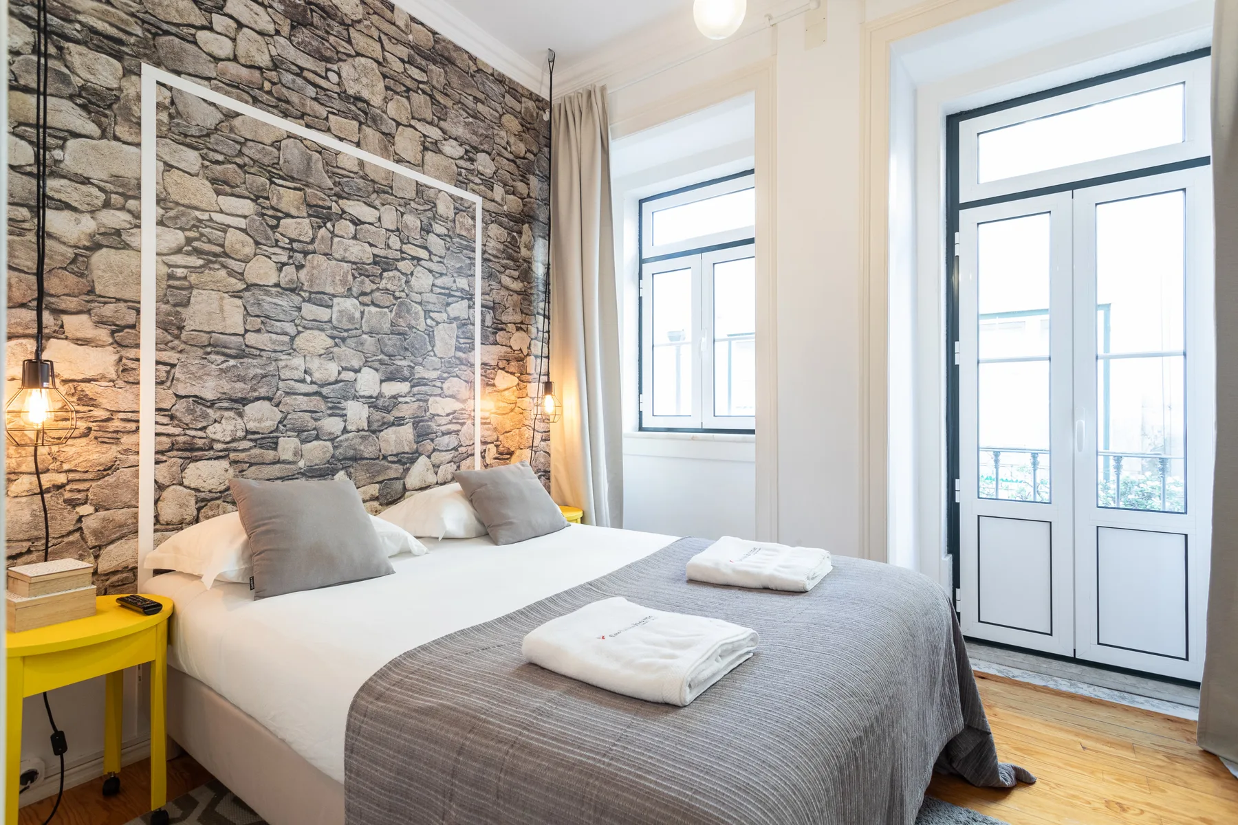 Un dormitorio con una cama bien hecha y ventanas amplias.