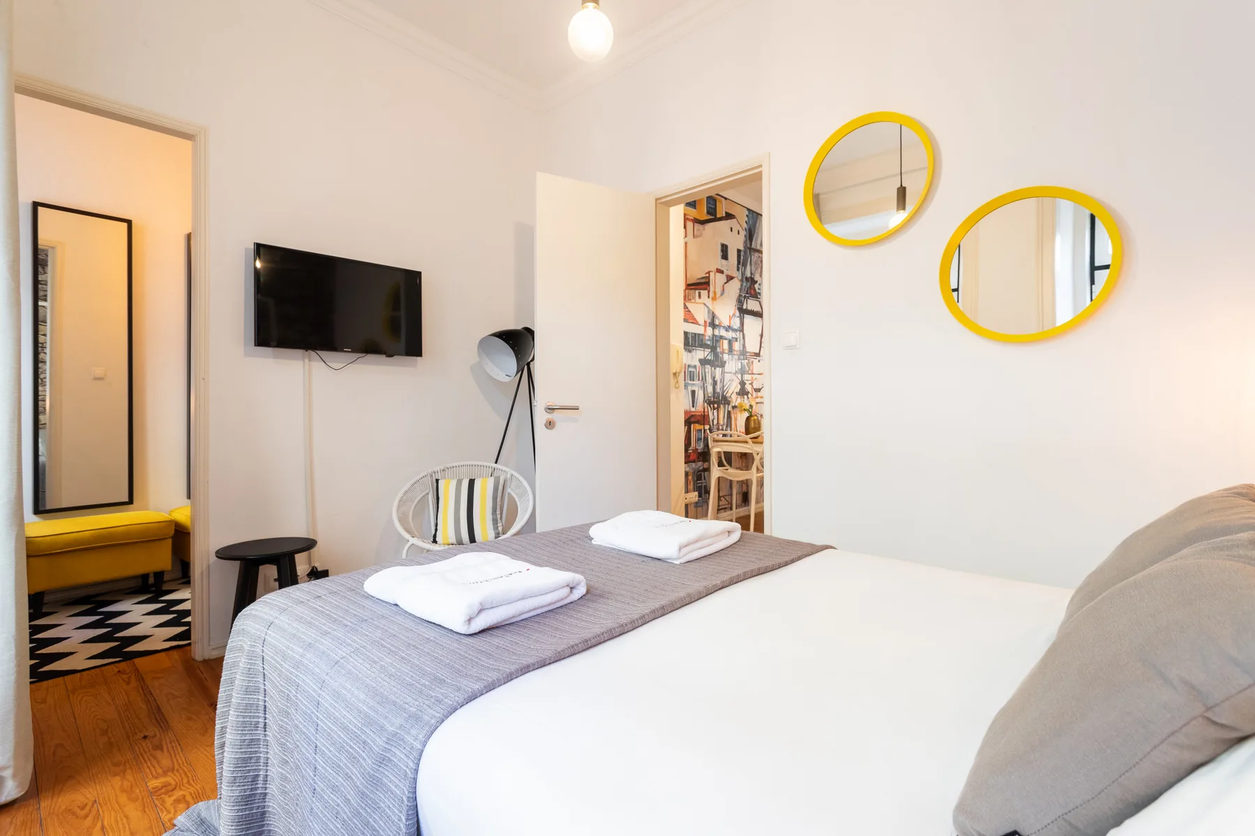 Un dormitorio con una cama tendida y un televisor montado en la pared.