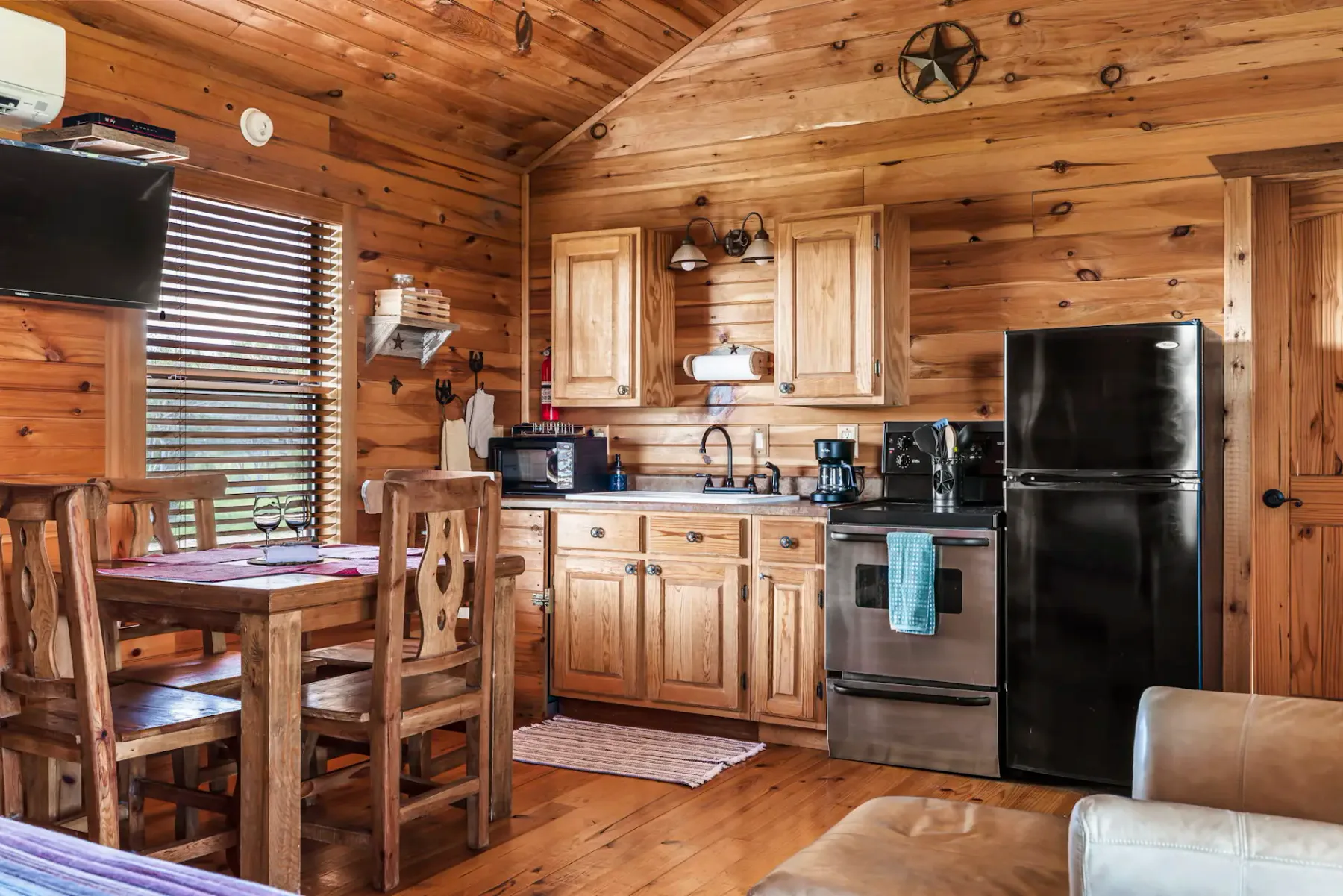 A wood-paneled kitchen and dining area with a table and stainless steel appliances.