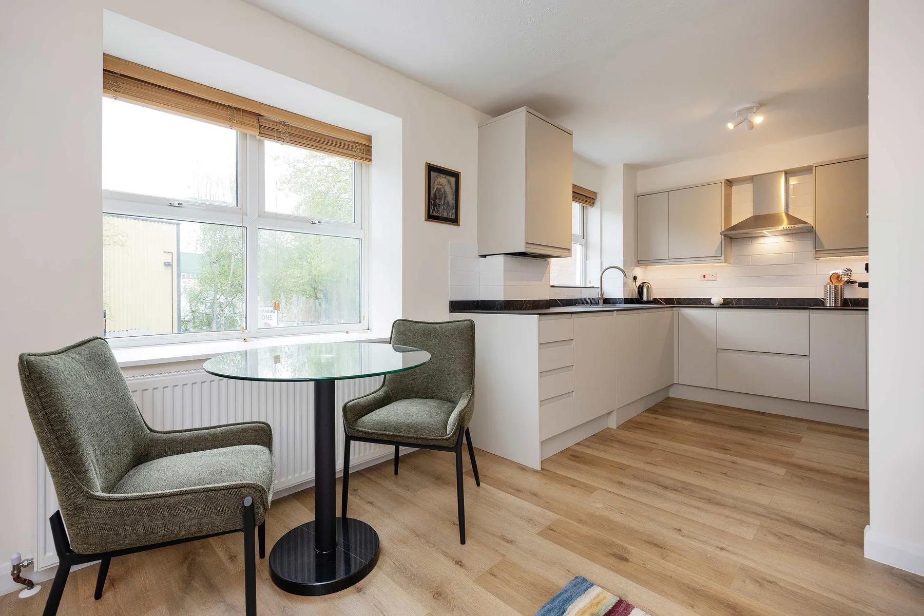 Una cocina luminosa con una mesa pequeña y asientos junto a una ventana grande.