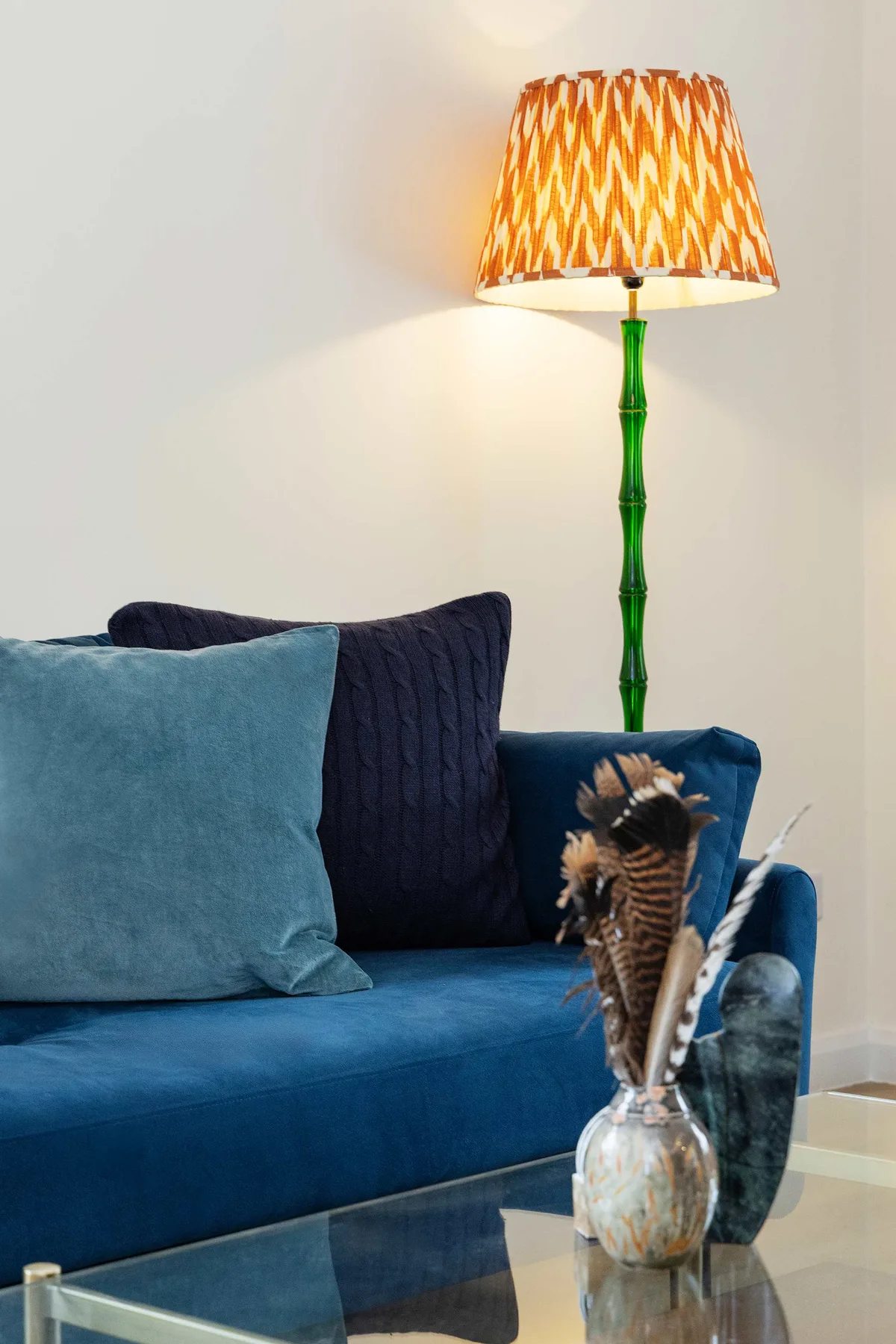 Una zona de estar con un sofá azul y una lámpara de pie encendida.