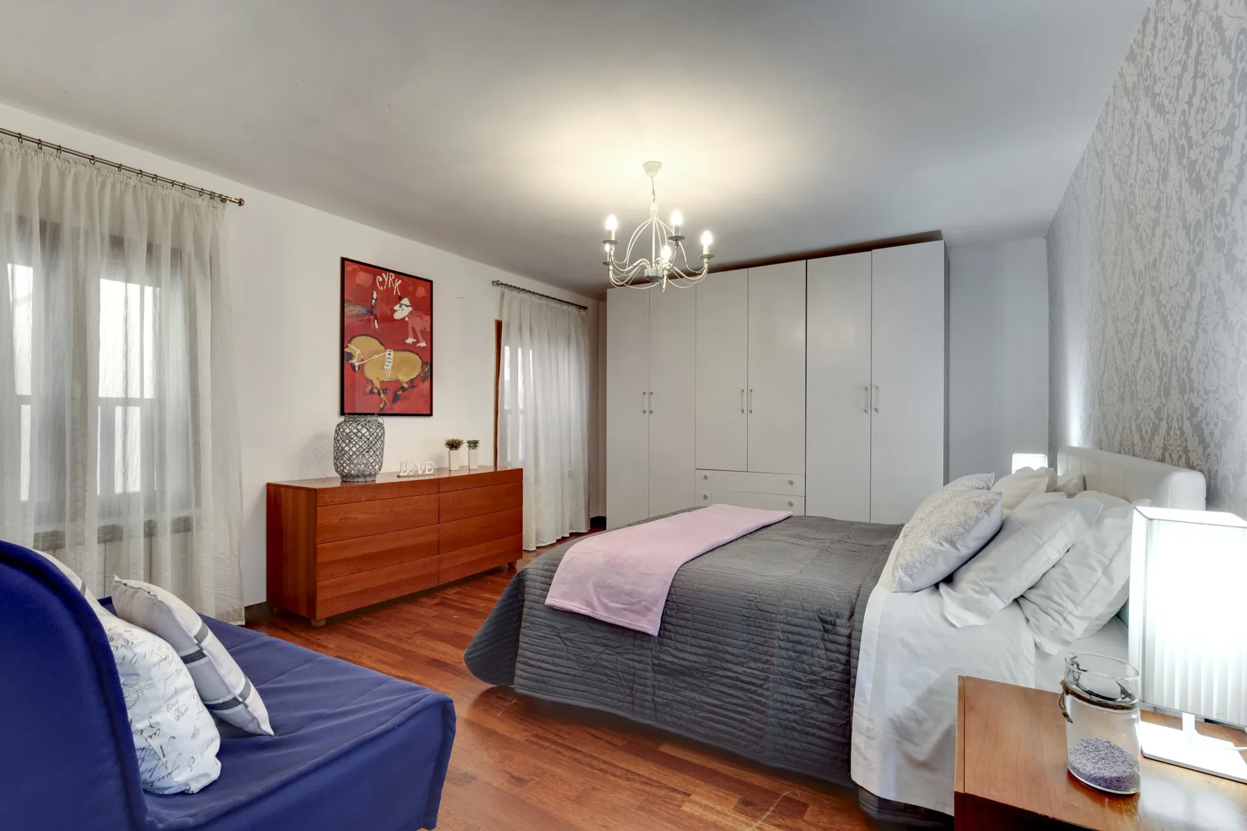 Un dormitorio con una cama, una cómoda y una zona de asientos azul.