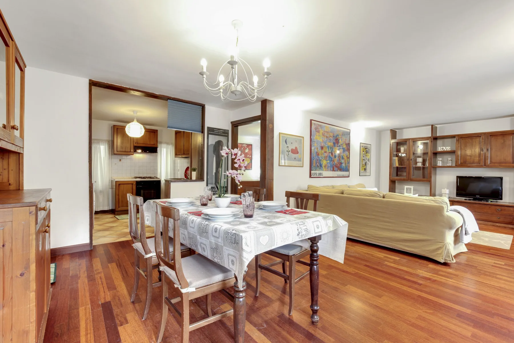 Comedor con la mesa puesta y sillas de madera junto a la sala de estar.