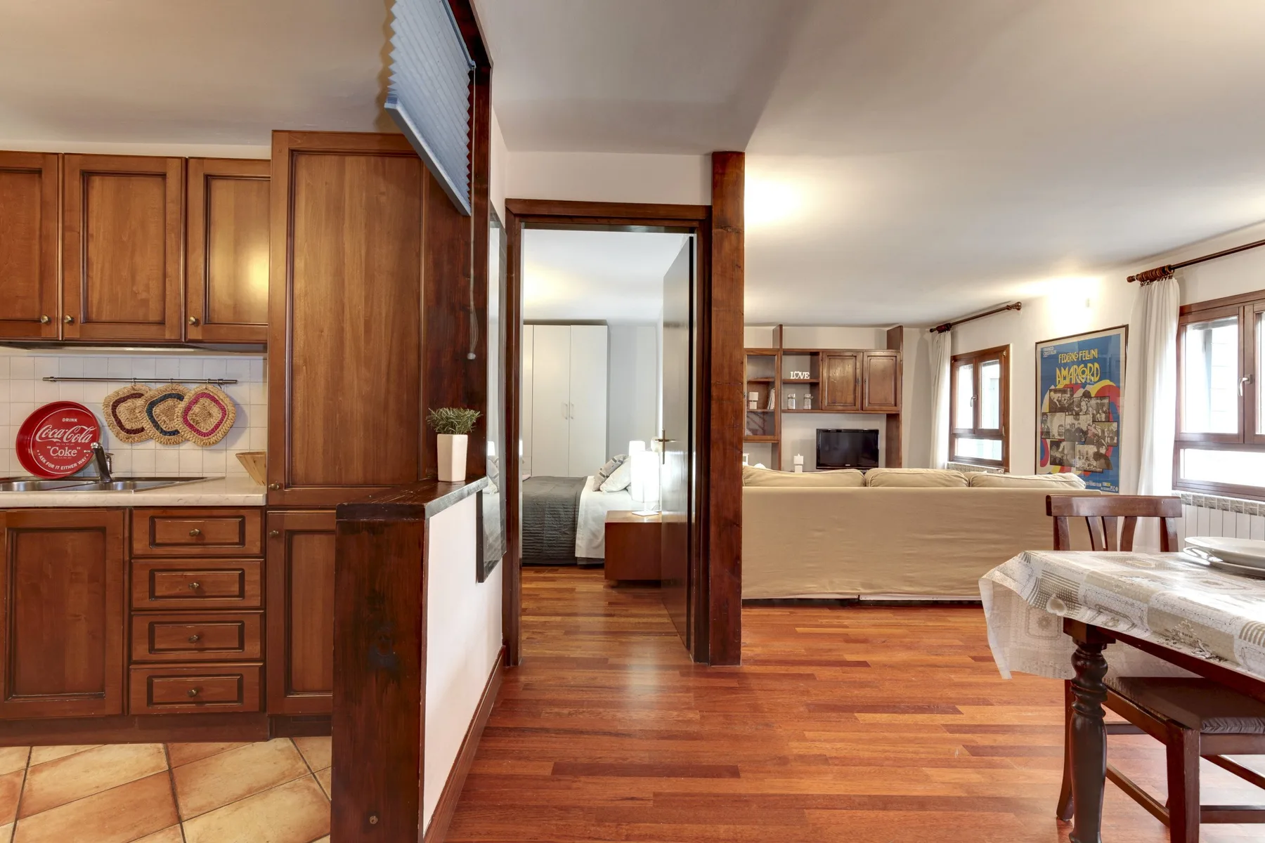 Una zona de estar abierta conecta una cocina con armarios de madera, una mesa de comedor y un área de asientos.