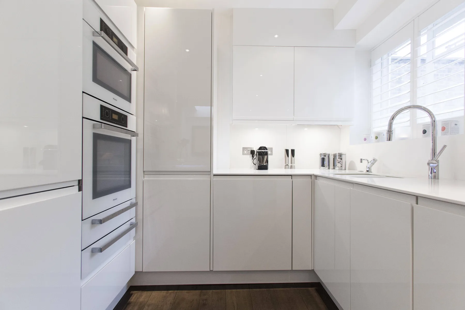 A bright modern kitchen with white cabinetry and built-in appliances.