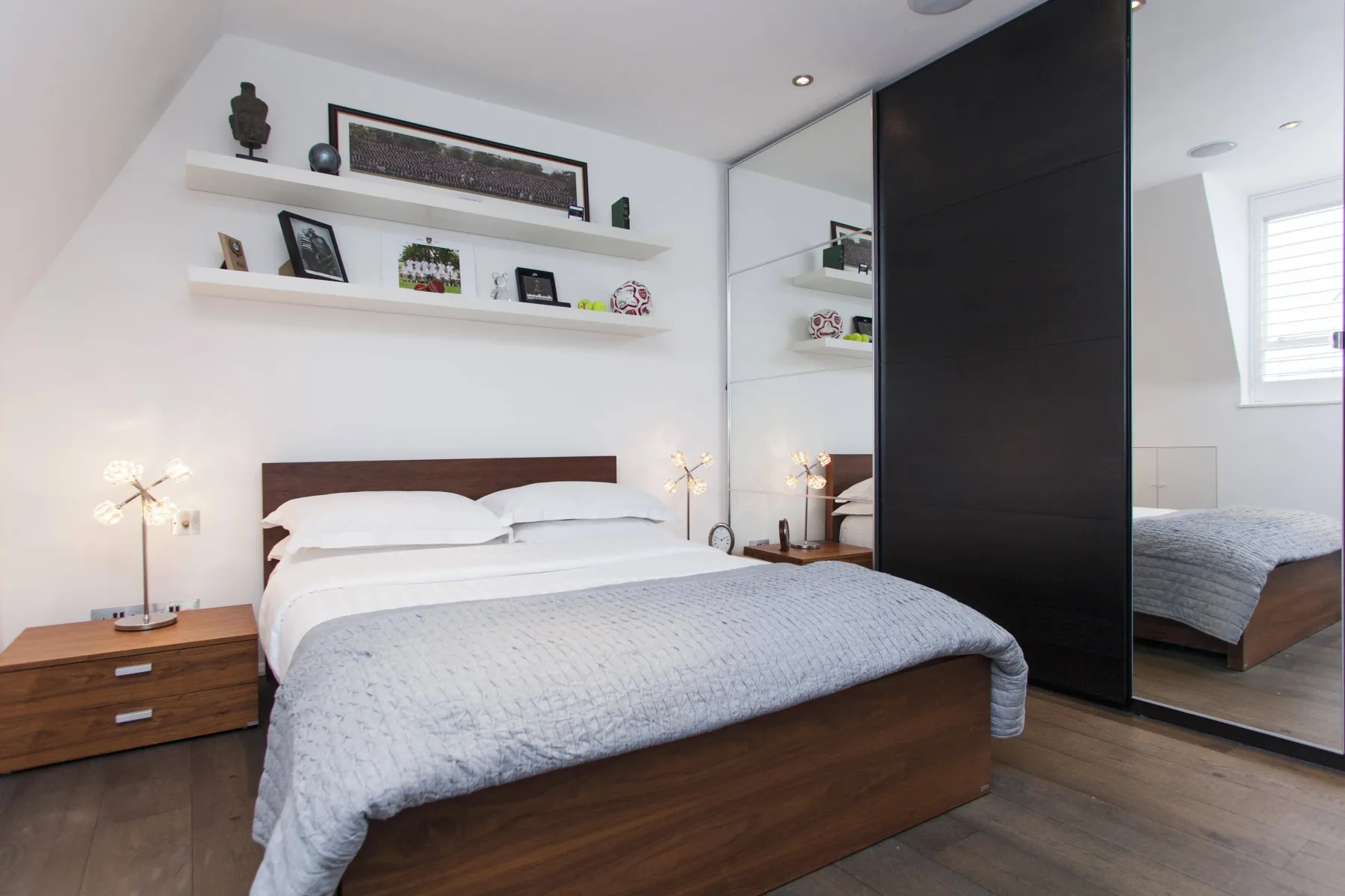 Un dormitorio con una cama bien tendida y estantes flotantes.
