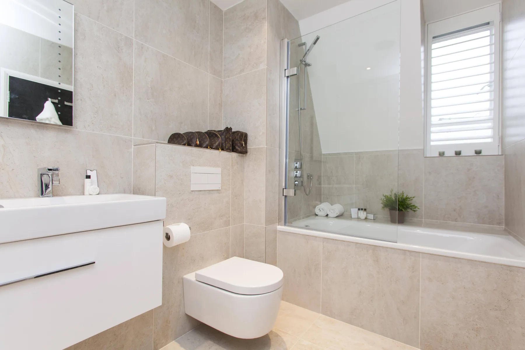 Un baño alicatado con lavabo, inodoro y bañera con ducha.