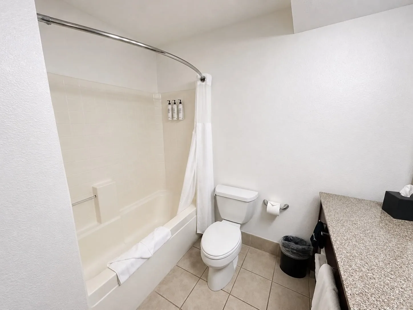 Family Suite bathroom with tub, shower curtain, toilet, and granite vanity