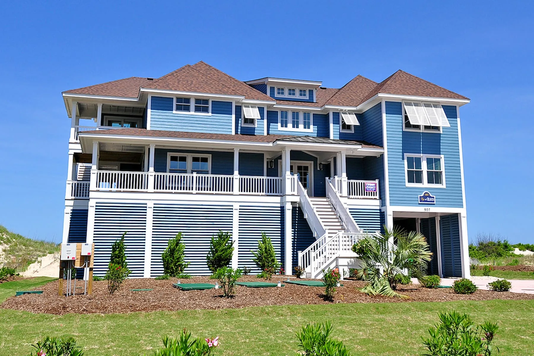 Una casa azul grande con porches blancos y escaleras exteriores.