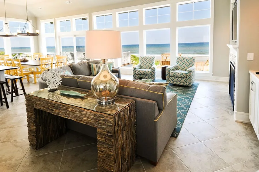 Una luminosa sala de estar con asientos y grandes ventanales con vista al mar.