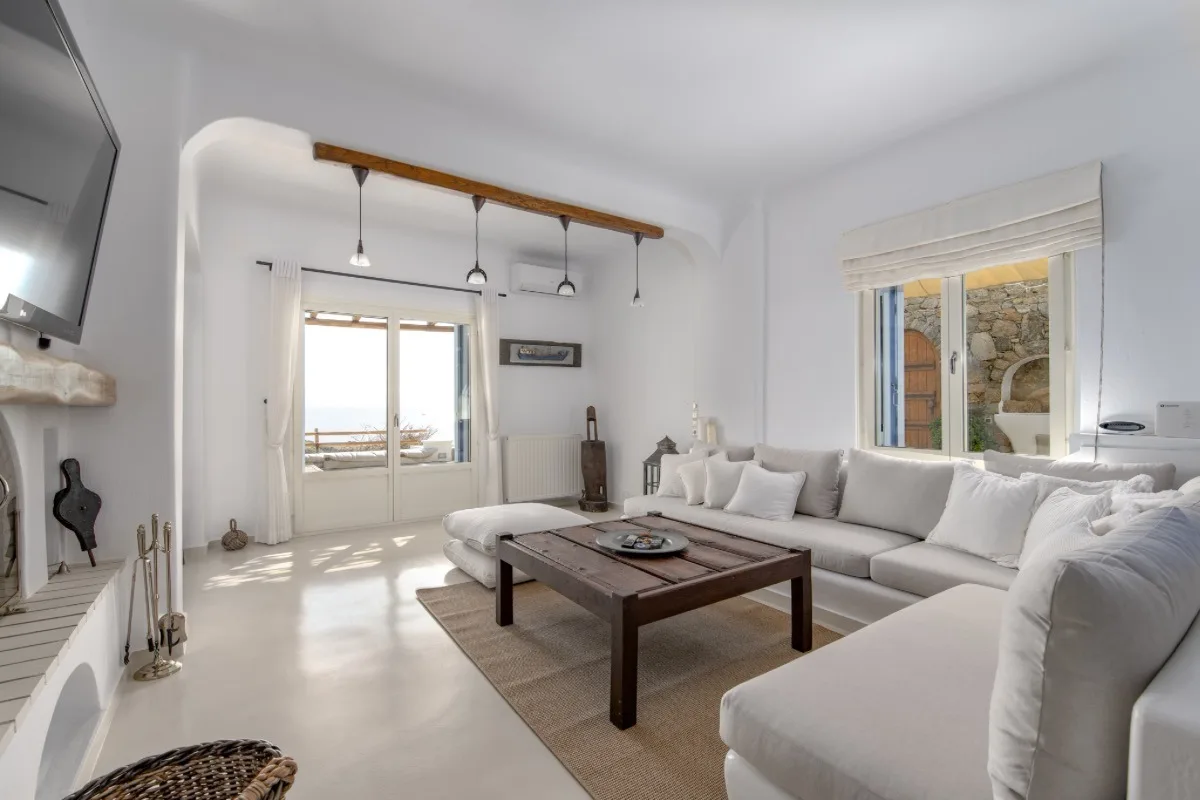 A bright living room with pale seating and a dark wooden coffee table.