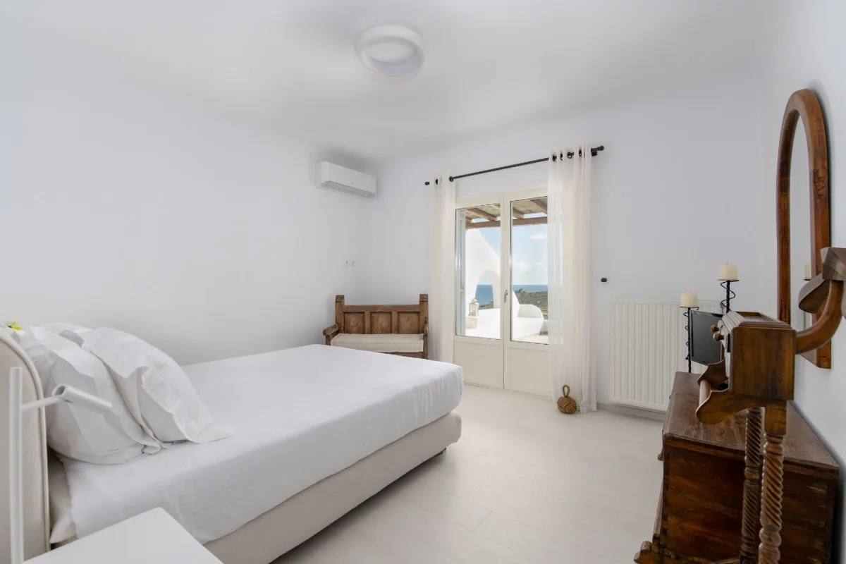 A bright bedroom with a bed and a glass door opening onto a balcony.