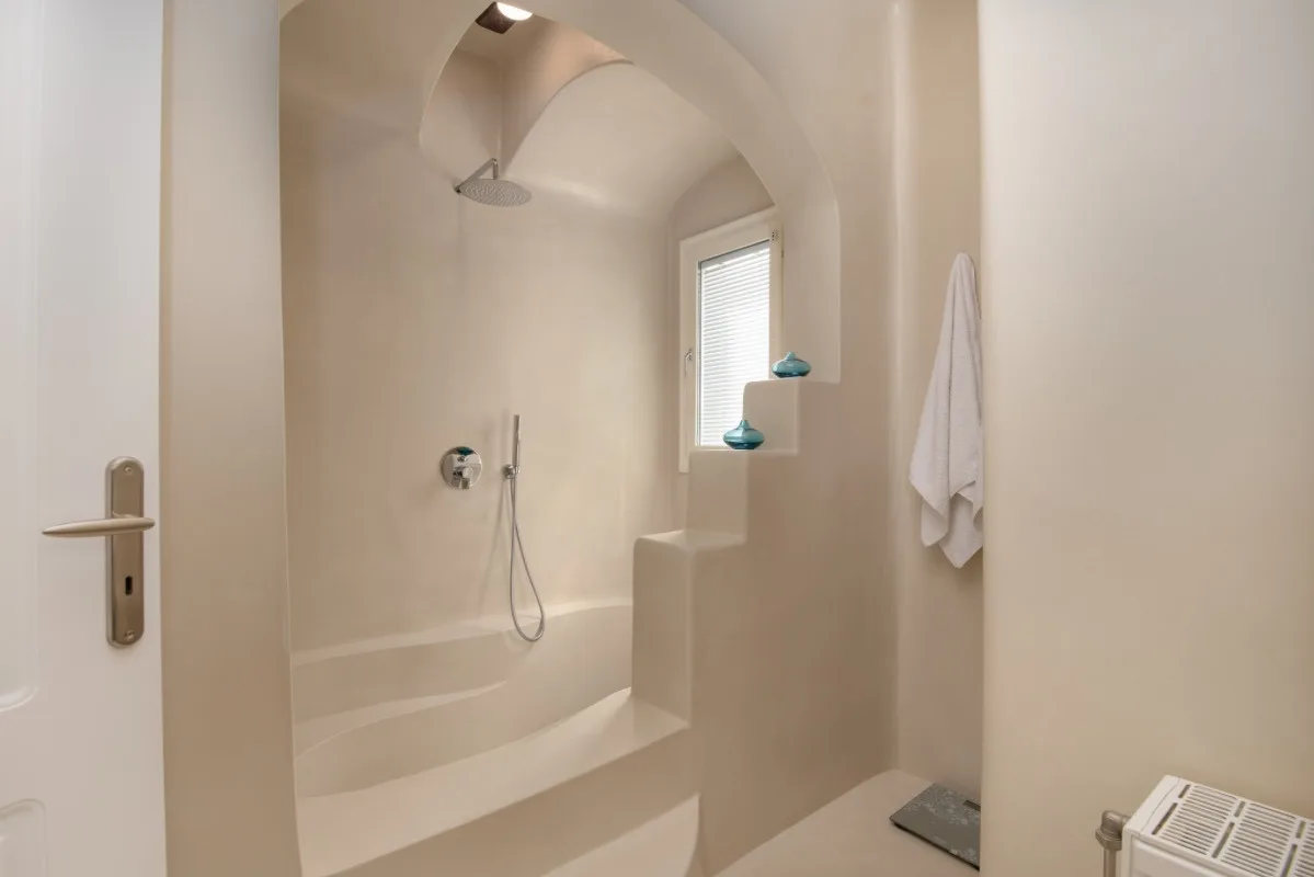 A bathroom with a built-in shower and a small window.