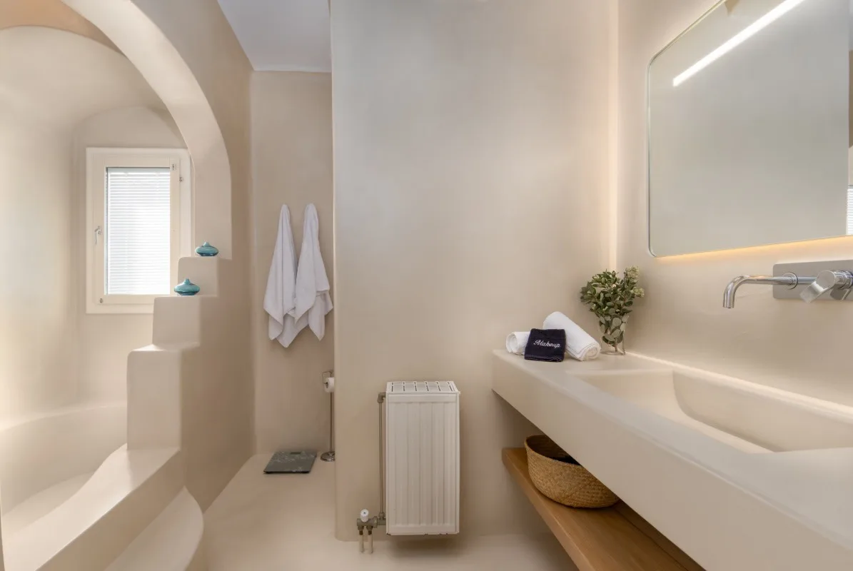 A bright bathroom with a built-in tub and a wide sink counter.