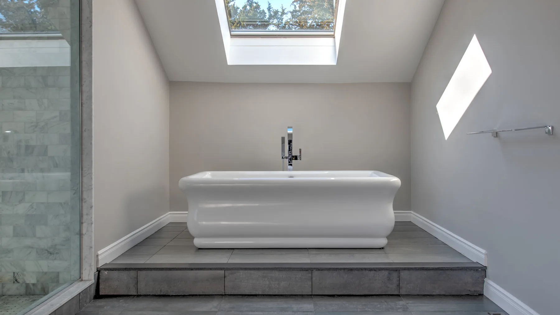 Un baño con una bañera exenta bajo una claraboya.