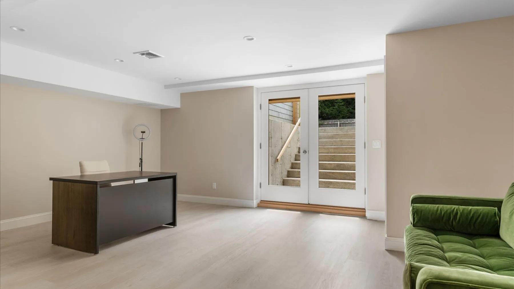 Una habitación luminosa con un escritorio y puertas de vidrio que dan a unos escalones exteriores.