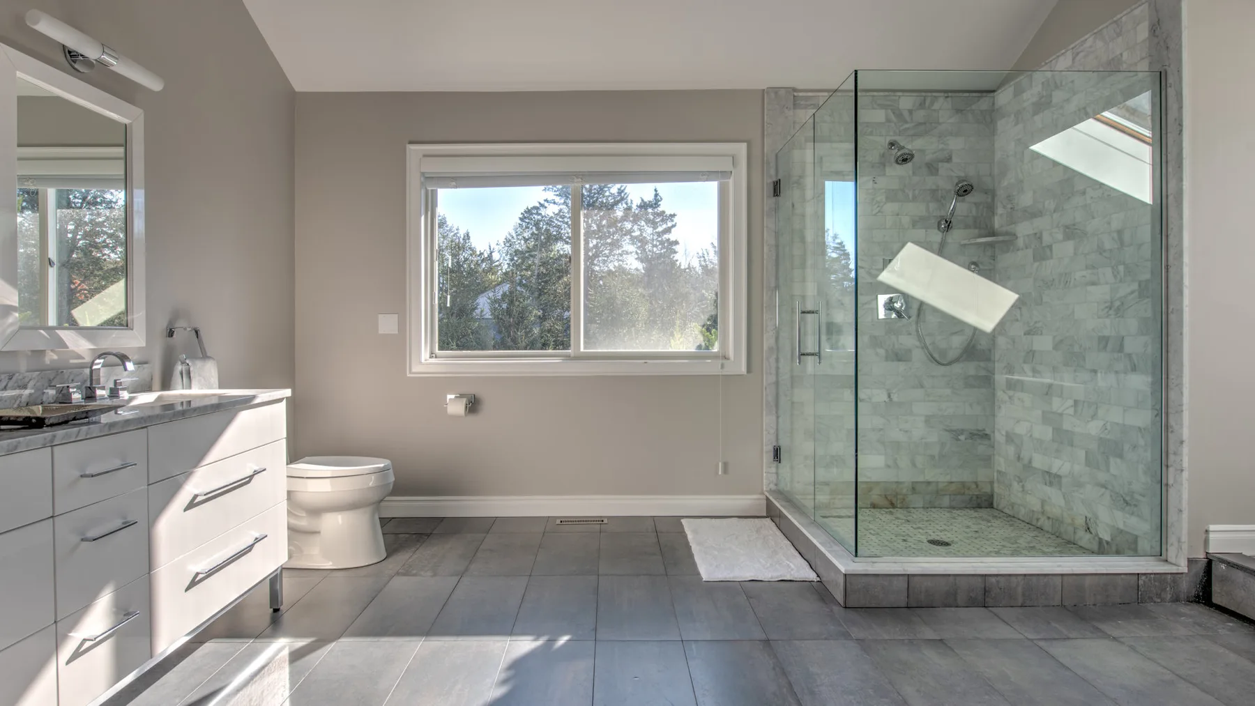 Un baño con lavabo, inodoro y ducha con mampara de vidrio.