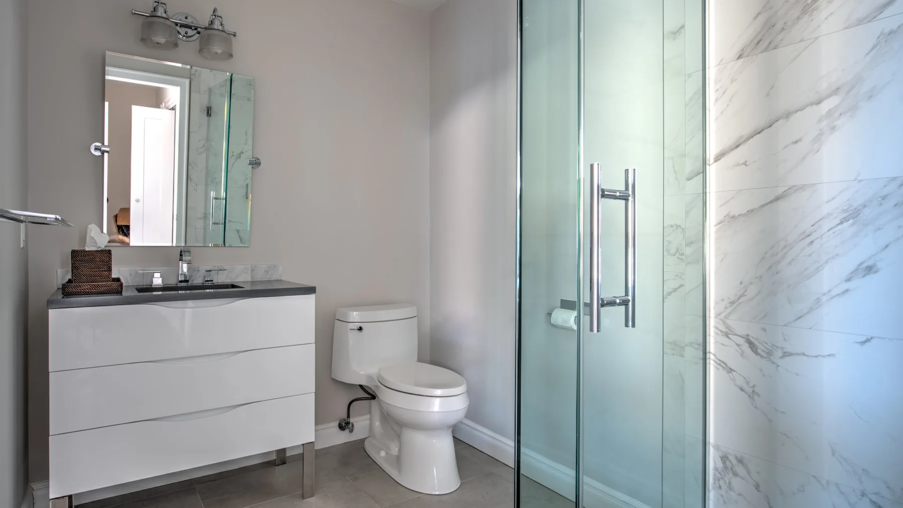 Un baño moderno con lavabo, inodoro y ducha de vidrio.